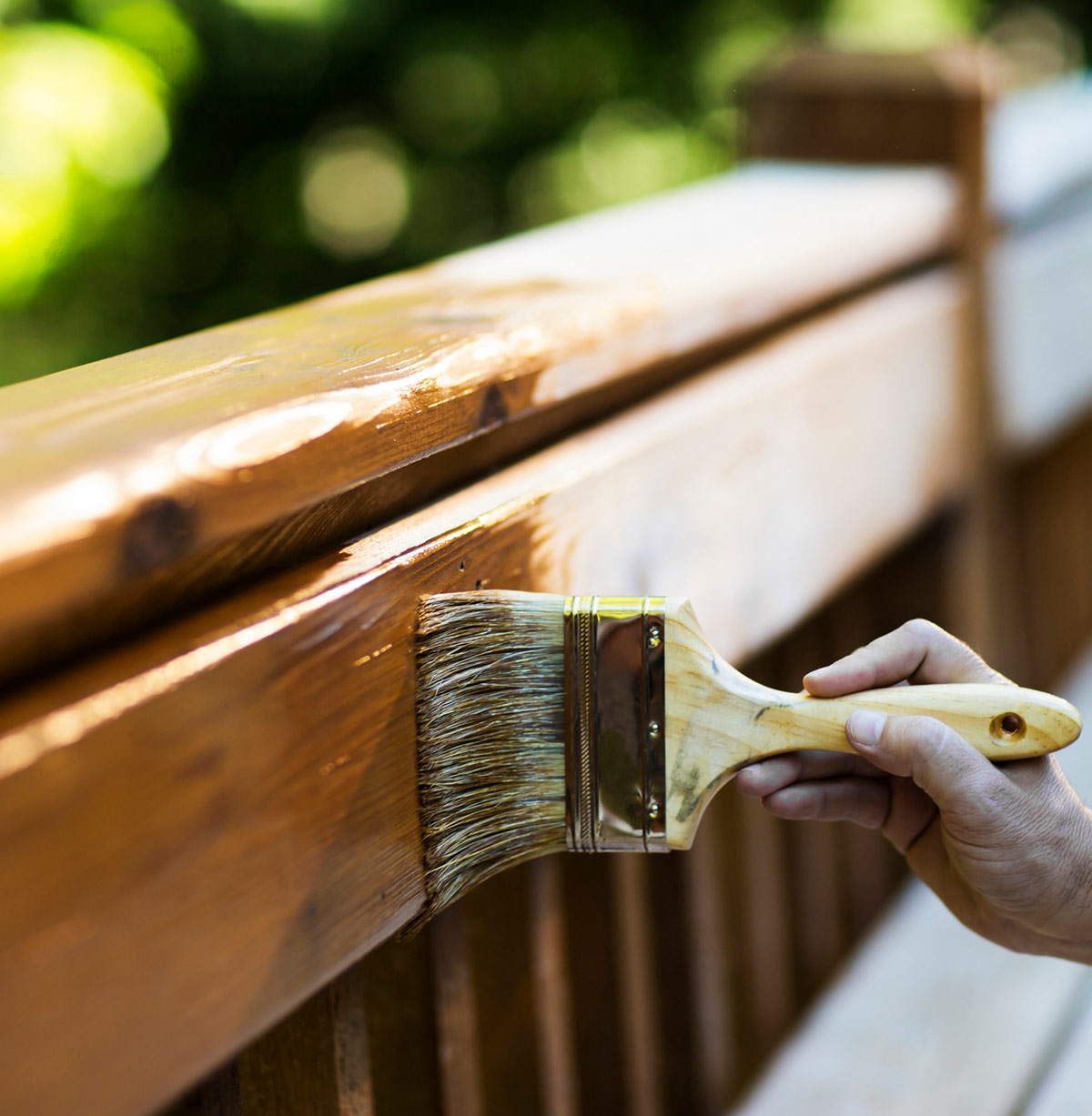 Male Carpenter Applying Varnish To Wooden Furniture